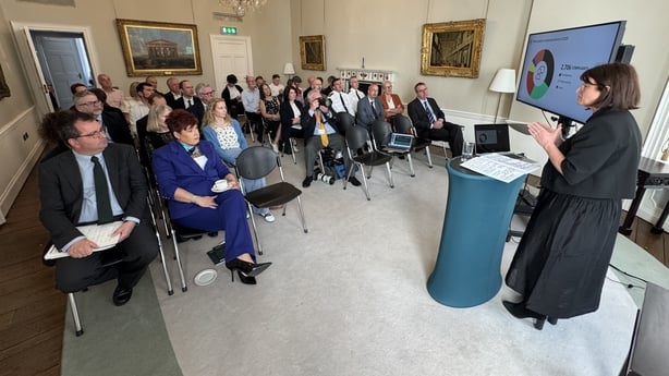 Ombudsman Emily Logan presenting Fiosrú's annual report for 2026 to a room full of people