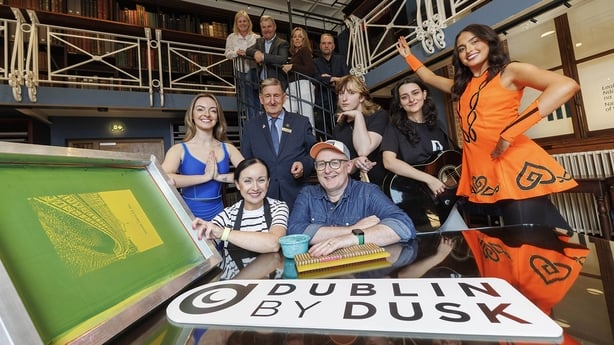 A number of people sit at a table with a Dublin by Dusk sign