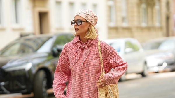 FRANKFURT AM MAIN, GERMANY - APRIL 21: Julia Kammerer is seen wearing a red and white gingham button down blouse from Pull&Bear; light blue pinstripe wide leg trousers from JJXX; a beige open-weave "Crochet tote bag" filled with lemons from Prada; a red a