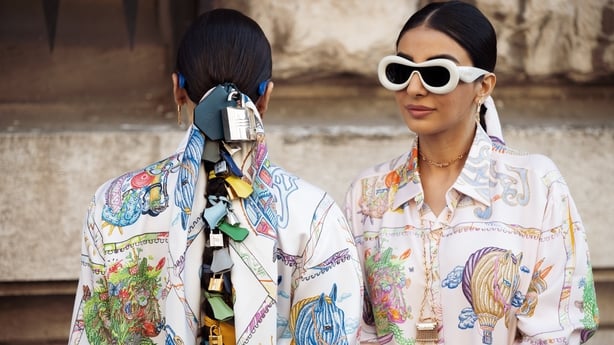 PARIS, FRANCE - MARCH 08: Sisters Snehal and Jyoti Babani wear white colourful printed silk shirt dress, blue sunglasses (L), and pink colourful silk printed shirt dress, white sunglasses (R) outside the Hermes fashion show during the Womenswear Fall/Winter 2025/2026 as part of Paris Fashion Week on