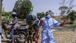 Health worker in protective gear gestures as he asks for help in transporting a patient suspected of having Ebola