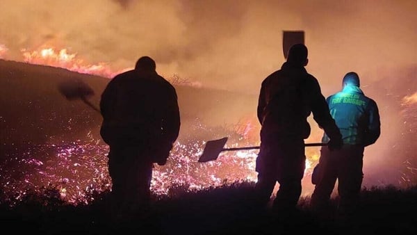 Firefighters are visible in the foreground as they face to a gorse fire in Dublin Mountains