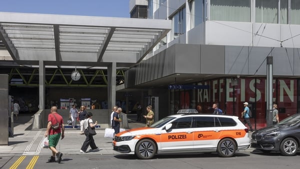 Commuters walk past a police vehicle parked in front of the central train station in Winterthur