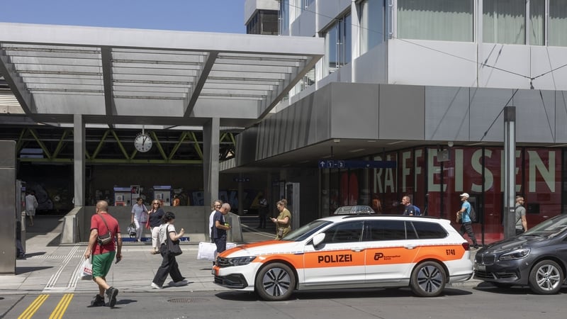 Commuters walk past a police vehicle parked in front of the central train station in Winterthur
