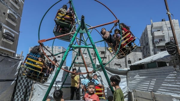 Palestinian children spend time on swings set up amid the rubble of buildings destroyed by Israeli attacks in Khan Yunis, Gaza