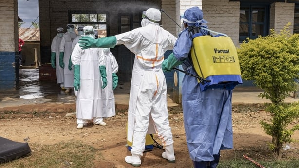 Health workers wearing protective equipment are disinfected after leaving an isolation area at a hospital in Mongbwalu, DR Congo 