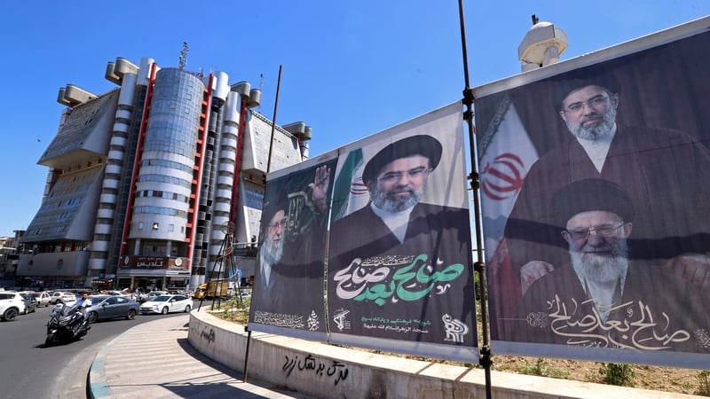Motorists drive past installed banners with pictures of Iran's slain supreme leader Ayatollah Ali Khamenei and his son and country's's newly nominated supreme leader Ayatollah Mojataba Khamenei at the Sadeghiyeh Square in Tehran