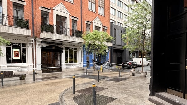 crime scene tape is pictured on a street with a black tarpaulin in the distance