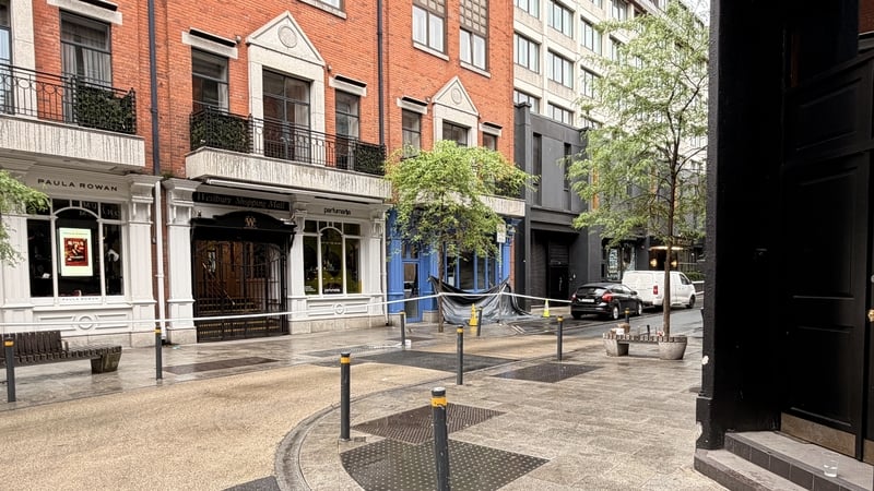 crime scene tape is pictured on a street with a black tarpaulin in the distance