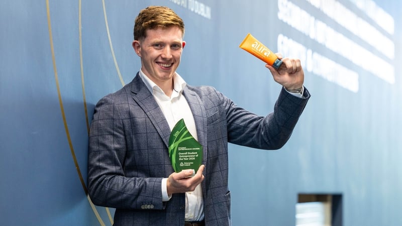 Image of a young business man holding up a tube of cream and an award