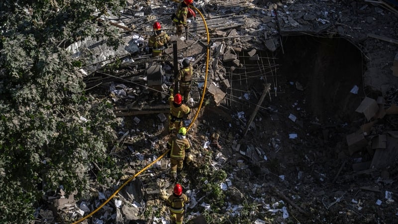 Rescue workers wearing red helmet seen working at the crater of a destroyed residential building in Kyiv