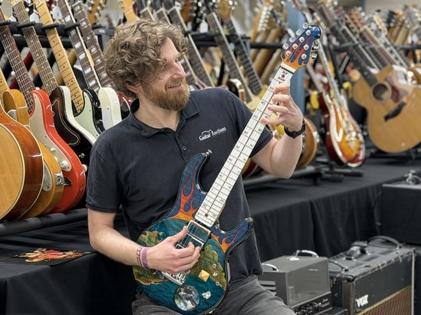 Auctioneer Luke Hobbs with the guitar used by spoof rock band Spinal Tap at the 2007 Wembley Live Earth concert. Photo: Gardiner Houlgate/PA Wire